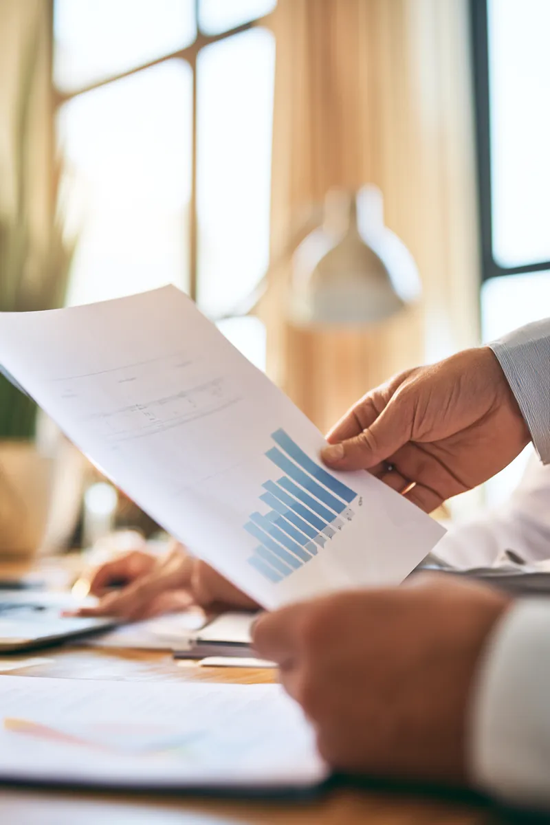 Hands comparing an auto repair loan rate chart on printed sheets